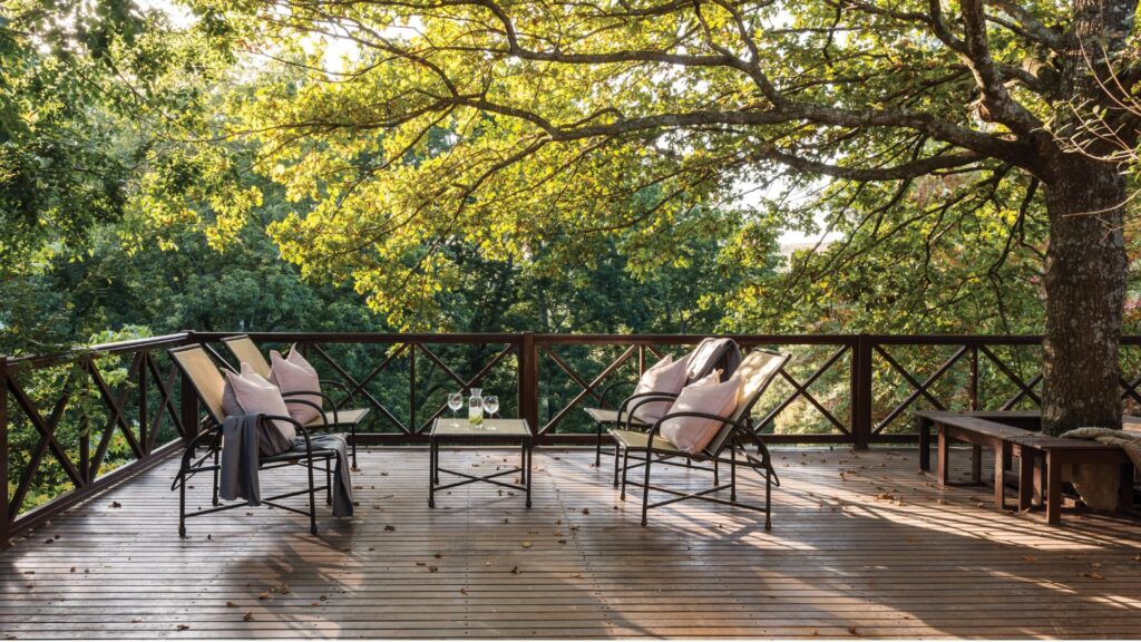A spa facility in a bush setting with four chairs on a wooden deck