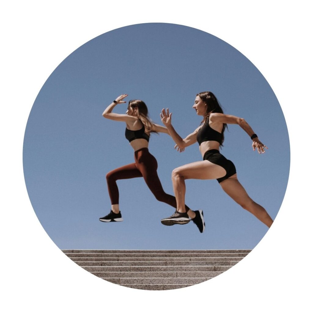 Two women running against blue backdrop