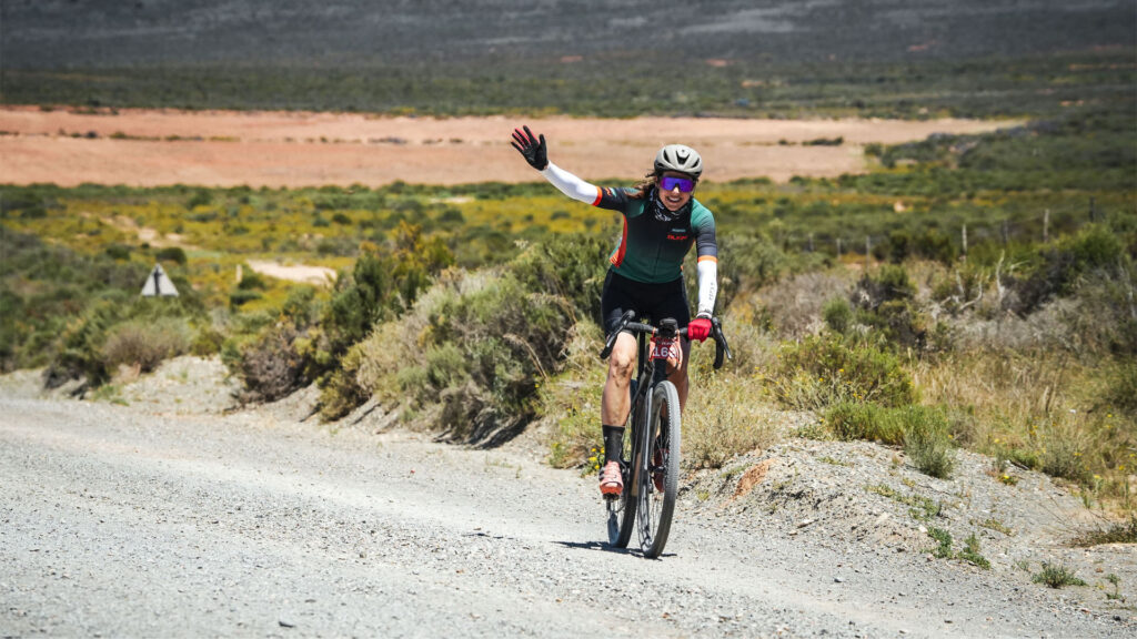 Woman waves while doing Nedbank Gravel Burn
